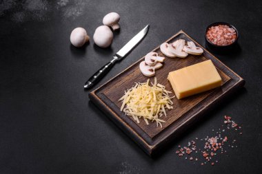 Çiğ makarna, mantar, soğan, kıyma, baharat ve otlar, domates soslu lezzetli bir macun yapmak için koyu beton arka planda.