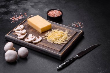 Çiğ makarna, mantar, soğan, kıyma, baharat ve otlar, domates soslu lezzetli bir macun yapmak için koyu beton arka planda.