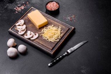 Çiğ makarna, mantar, soğan, kıyma, baharat ve otlar, domates soslu lezzetli bir macun yapmak için koyu beton arka planda.