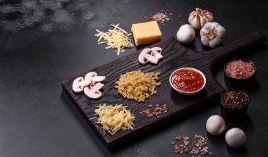 Çiğ makarna, mantar, soğan, kıyma, baharat ve otlar, domates soslu lezzetli bir macun yapmak için koyu beton arka planda.