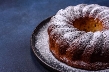 Ev yapımı, yuvarlak, kırmızı böğürtlenli ve seramik tabakta koyu beton arka planda yuvarlak bir Noel pastası.