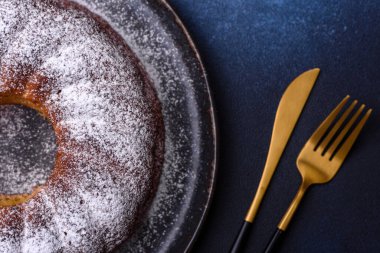 Ev yapımı, yuvarlak, kırmızı böğürtlenli ve seramik tabakta koyu beton arka planda yuvarlak bir Noel pastası.