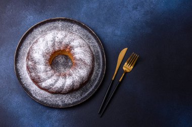 Ev yapımı, yuvarlak, kırmızı böğürtlenli ve seramik tabakta koyu beton arka planda yuvarlak bir Noel pastası.