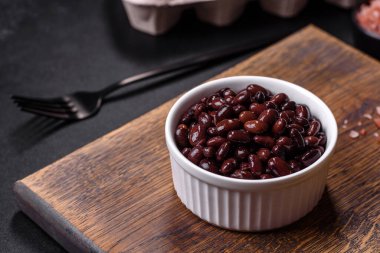 Siyah, konserve fasulye ve beyaz çay tabağı ile koyu beton bir arka plan. Vejeteryan yemeklere karşı saygısızdırlar.