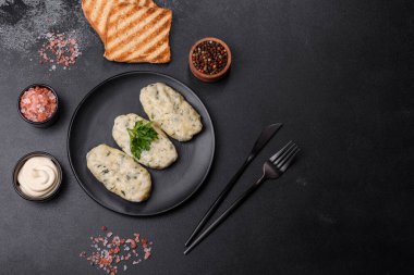 Geleneksel Litvanya yemeği zeplini, haşlanmış patates köfteleri kıyma ile doldurulmuş siyah seramik tabakta koyu beton arka planda.