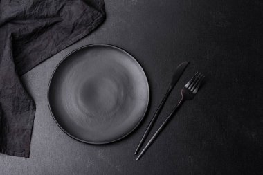 Beton bir masada siyah çatal bıçak takımı. Yemek masası hazırlığı