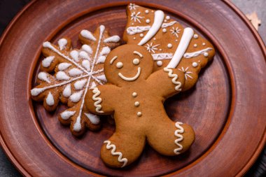 Kahverengi seramik tabakta güzel zencefilli ekmek ve koyu beton arka planda Noel ağacı süslemeleri. Noel için eve hazırlanıyorum.