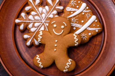 Kahverengi seramik tabakta güzel zencefilli ekmek ve koyu beton arka planda Noel ağacı süslemeleri. Noel için eve hazırlanıyorum.