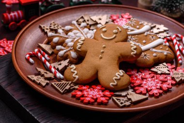 Kahverengi seramik tabakta güzel zencefilli ekmek ve koyu beton arka planda Noel ağacı süslemeleri. Noel için eve hazırlanıyorum.