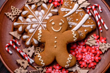 Kahverengi seramik tabakta güzel zencefilli ekmek ve koyu beton arka planda Noel ağacı süslemeleri. Noel için eve hazırlanıyorum.