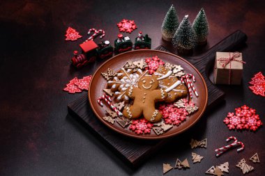 Kahverengi seramik tabakta güzel zencefilli ekmek ve koyu beton arka planda Noel ağacı süslemeleri. Noel için eve hazırlanıyorum.