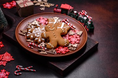 Kahverengi seramik tabakta güzel zencefilli ekmek ve koyu beton arka planda Noel ağacı süslemeleri. Noel için eve hazırlanıyorum.