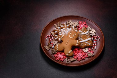 Kahverengi seramik tabakta güzel zencefilli ekmek ve koyu beton arka planda Noel ağacı süslemeleri. Noel için eve hazırlanıyorum.
