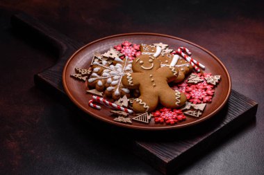 Kahverengi seramik tabakta güzel zencefilli ekmek ve koyu beton arka planda Noel ağacı süslemeleri. Noel için eve hazırlanıyorum.