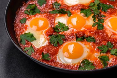 Shakshuka, domates soslu sahanda yumurta, tatlı biber, sarımsak, soğan, baharat ve bitkilerle dolu bir yemek. Yürekli ve lezzetli kahvaltı.