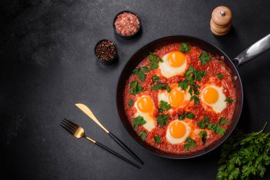 Shakshuka, domates soslu sahanda yumurta, tatlı biber, sarımsak, soğan, baharat ve bitkilerle dolu bir yemek. Yürekli ve lezzetli kahvaltı.