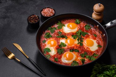 Shakshuka, domates soslu sahanda yumurta, tatlı biber, sarımsak, soğan, baharat ve bitkilerle dolu bir yemek. Yürekli ve lezzetli kahvaltı.