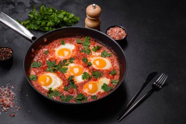Shakshuka, domates soslu sahanda yumurta, tatlı biber, sarımsak, soğan, baharat ve bitkilerle dolu bir yemek. Yürekli ve lezzetli kahvaltı.