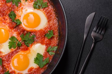 Shakshuka, domates soslu sahanda yumurta, tatlı biber, sarımsak, soğan, baharat ve bitkilerle dolu bir yemek. Yürekli ve lezzetli kahvaltı.