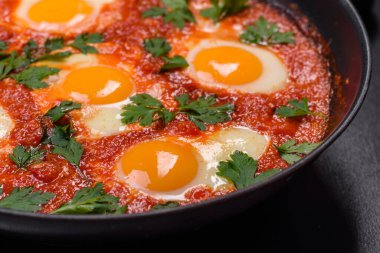 Shakshuka, domates soslu sahanda yumurta, tatlı biber, sarımsak, soğan, baharat ve bitkilerle dolu bir yemek. Yürekli ve lezzetli kahvaltı.