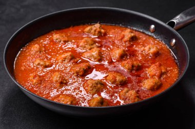 Siyah tavada servis edilen baharatlı domates soslu kıymadan yapılan lezzetli köfteler.