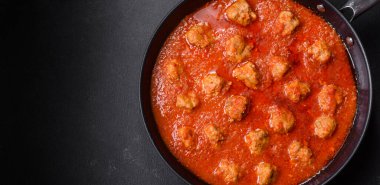 Siyah tavada servis edilen baharatlı domates soslu kıymadan yapılan lezzetli köfteler.