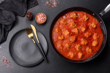 Siyah tavada servis edilen baharatlı domates soslu kıymadan yapılan lezzetli köfteler.