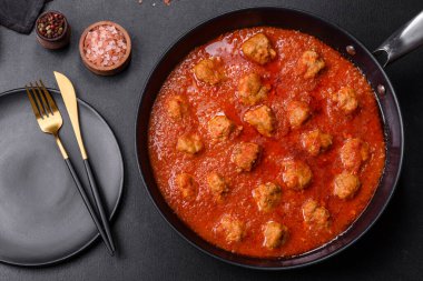 Siyah tavada servis edilen baharatlı domates soslu kıymadan yapılan lezzetli köfteler.