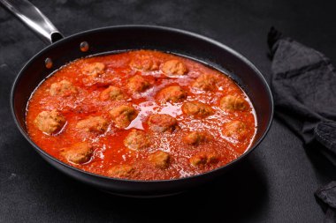 Siyah tavada servis edilen baharatlı domates soslu kıymadan yapılan lezzetli köfteler.