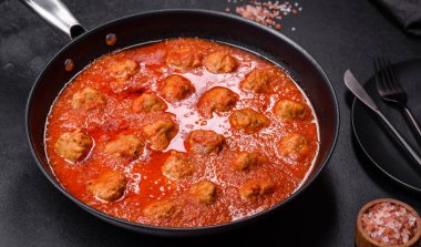 Siyah tavada servis edilen baharatlı domates soslu kıymadan yapılan lezzetli köfteler.