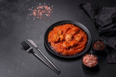 Siyah tavada servis edilen baharatlı domates soslu kıymadan yapılan lezzetli köfteler.