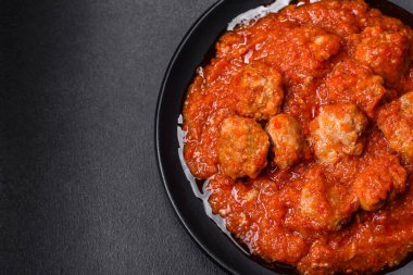 Siyah tavada servis edilen baharatlı domates soslu kıymadan yapılan lezzetli köfteler.