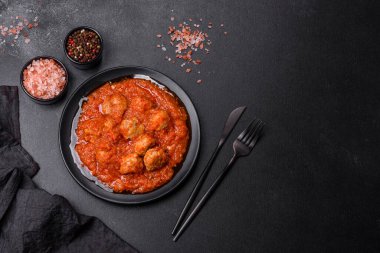 Siyah tavada servis edilen baharatlı domates soslu kıymadan yapılan lezzetli köfteler.