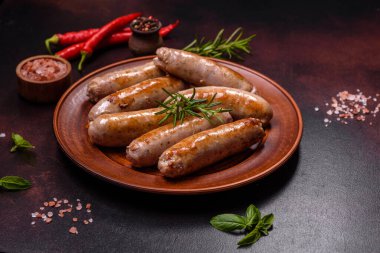 Baharatlı ızgara sosis ve koyu beton arka planda tuz ve biberli otlar. Açık ateşte pişmiş et yemeği.