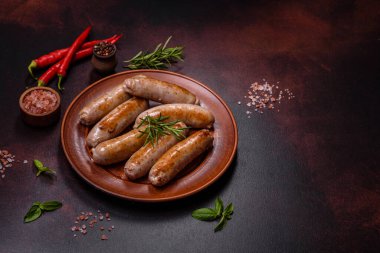 Baharatlı ızgara sosis ve koyu beton arka planda tuz ve biberli otlar. Açık ateşte pişmiş et yemeği.