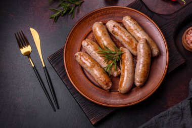 Baharatlı ızgara sosis ve koyu beton arka planda tuz ve biberli otlar. Açık ateşte pişmiş et yemeği.