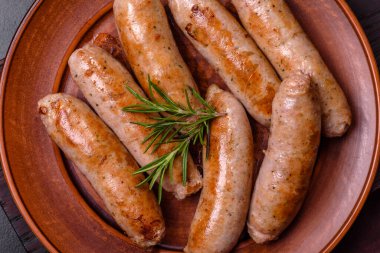 Baharatlı ızgara sosis ve koyu beton arka planda tuz ve biberli otlar. Açık ateşte pişmiş et yemeği.