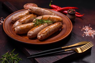 Baharatlı ızgara sosis ve koyu beton arka planda tuz ve biberli otlar. Açık ateşte pişmiş et yemeği.