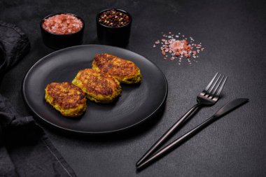 Kabak, havuç ve koyu beton bir masada siyah bir tabakta bulunan bitkilerden alınmış diyet sebze pirzesi. Sağlıklı yemek.