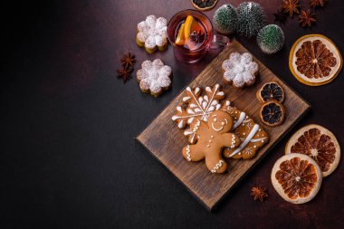 Bir dilim portakallı sıcak şarap, tarçın, karanfil ve diğer baharatlarla çikolatalı kekler ve koyu beton arka planda Noel süslemeleri.