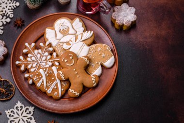 Bir dilim portakallı sıcak şarap, tarçın, karanfil ve diğer baharatlarla çikolatalı kekler ve koyu beton arka planda Noel süslemeleri.