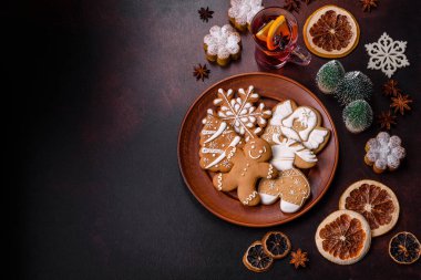 Bir dilim portakallı sıcak şarap, tarçın, karanfil ve diğer baharatlarla çikolatalı kekler ve koyu beton arka planda Noel süslemeleri.