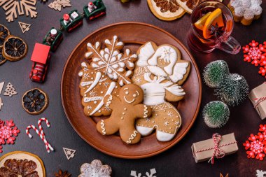 Bir dilim portakallı sıcak şarap, tarçın, karanfil ve diğer baharatlarla çikolatalı kekler ve koyu beton arka planda Noel süslemeleri.