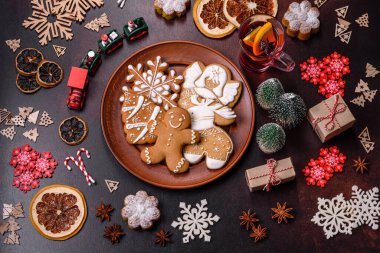 Bir dilim portakallı sıcak şarap, tarçın, karanfil ve diğer baharatlarla çikolatalı kekler ve koyu beton arka planda Noel süslemeleri.