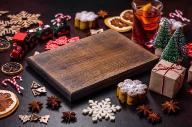Bir dilim portakallı sıcak şarap, tarçın, karanfil ve diğer baharatlarla çikolatalı kekler ve koyu beton arka planda Noel süslemeleri.