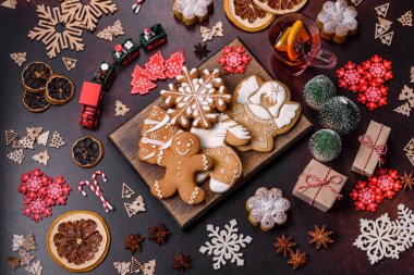 Bir dilim portakallı sıcak şarap, tarçın, karanfil ve diğer baharatlarla çikolatalı kekler ve koyu beton arka planda Noel süslemeleri.