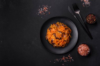 Sarımsaklı, siyah desenli bir tabakta havuçlu Kore salatası ve patlıcan.