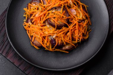 Sarımsaklı, siyah desenli bir tabakta havuçlu Kore salatası ve patlıcan.