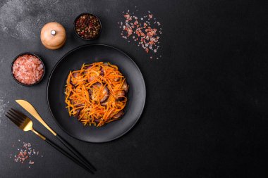 Sarımsaklı, siyah desenli bir tabakta havuçlu Kore salatası ve patlıcan.