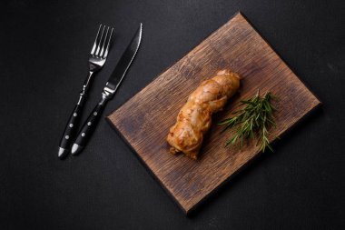 Lezzetli fırınlanmış et rulosu tavuk eti, baharatlı tatlı biber ve ahşap kesme tahtasındaki otlar.